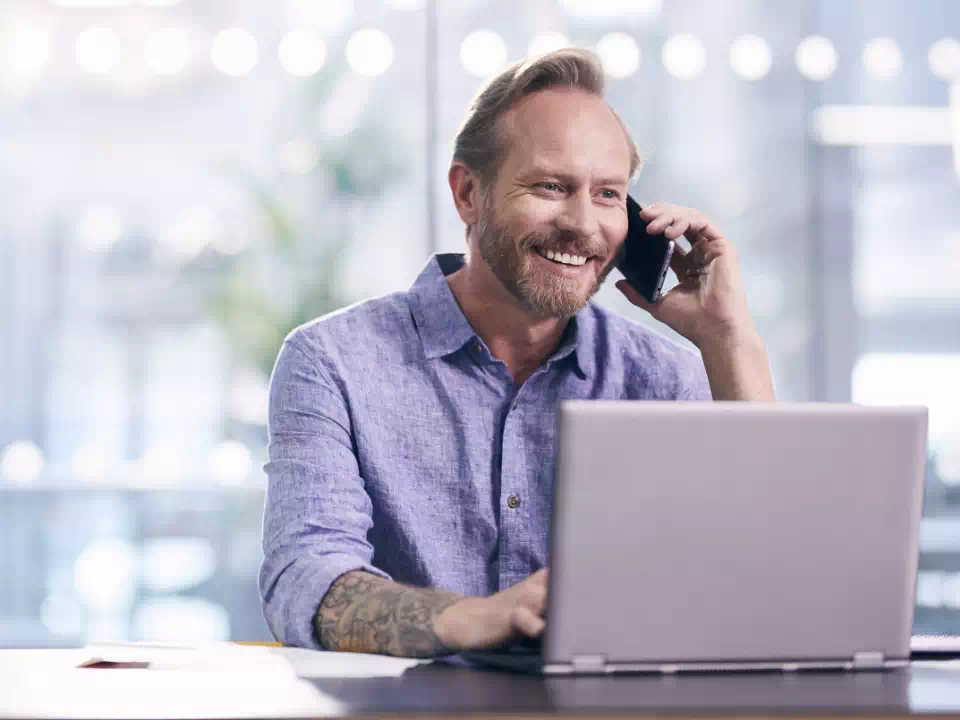 mężczyzna rozmawiający przez telefon przed laptopem